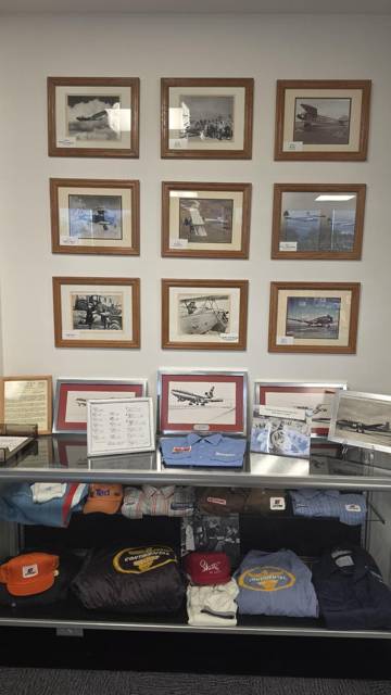 Wall of framed aviation photographs above caps and apparel
